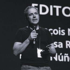 Photo of François Musseau holding a microphone and speaking on a stage.