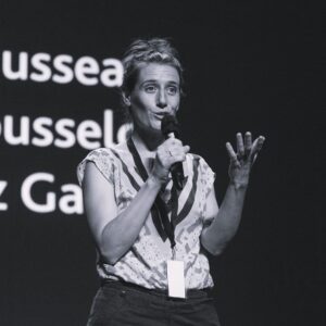 Vanessa Rousselot holding a microphone and speaking on a stage
